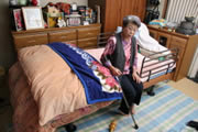 Kimie Kishi se sienta en la cama ortopédica que puede estar a punto de perder. (Takeshi Nishimura / © Mainichi Shimbun)